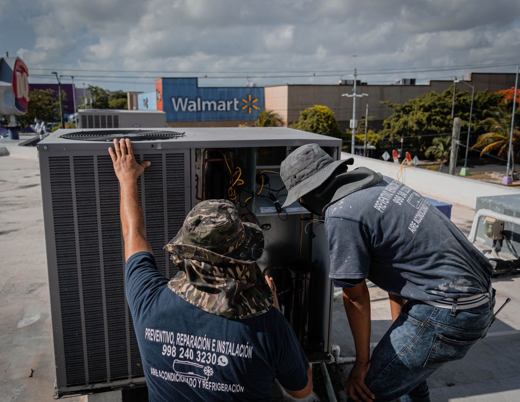 Two technicians repair a rooftop HVAC unit.